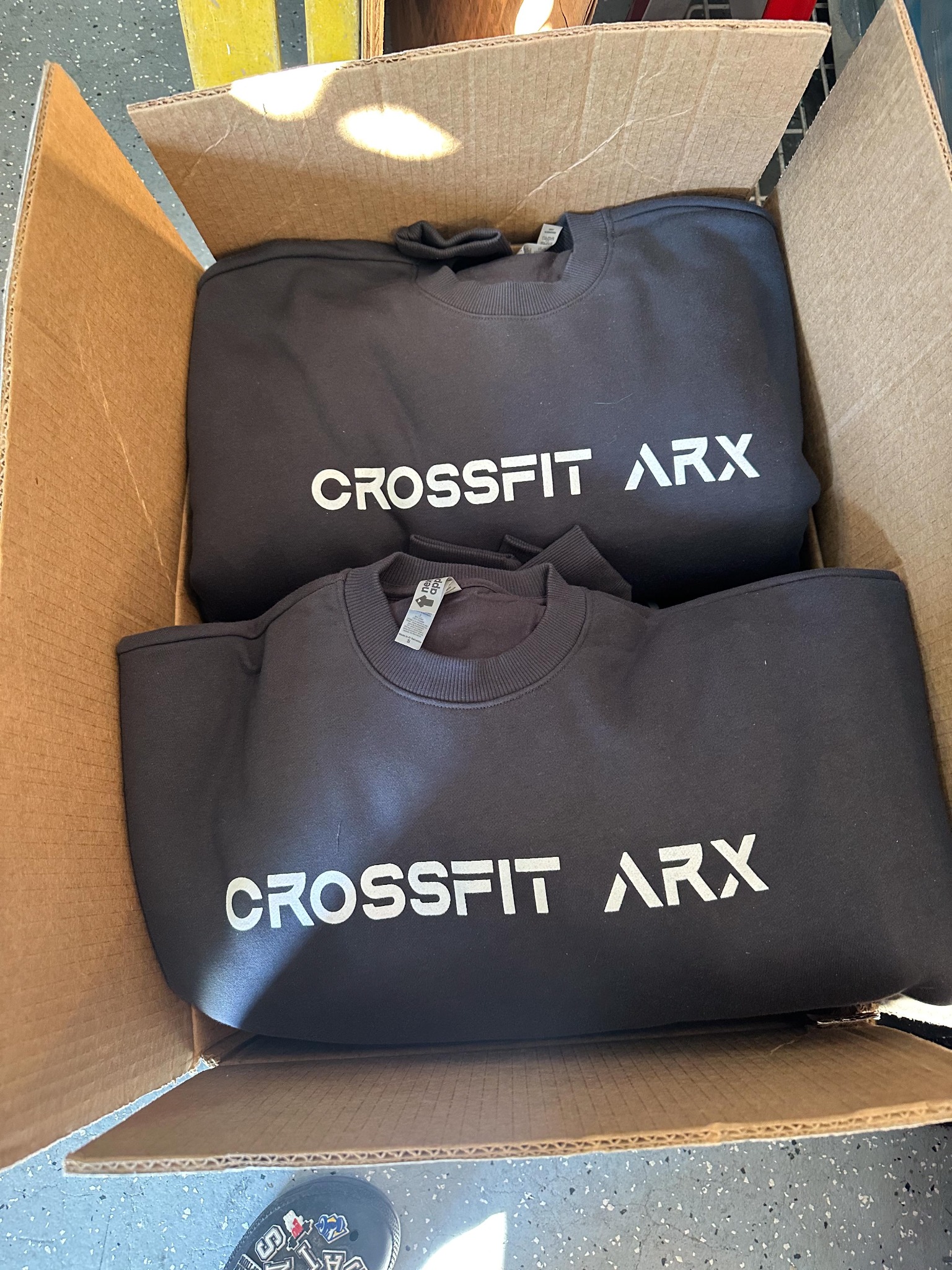 Dark CrossFit ARX crewneck sweatshirts with white logo prints packed in a box
