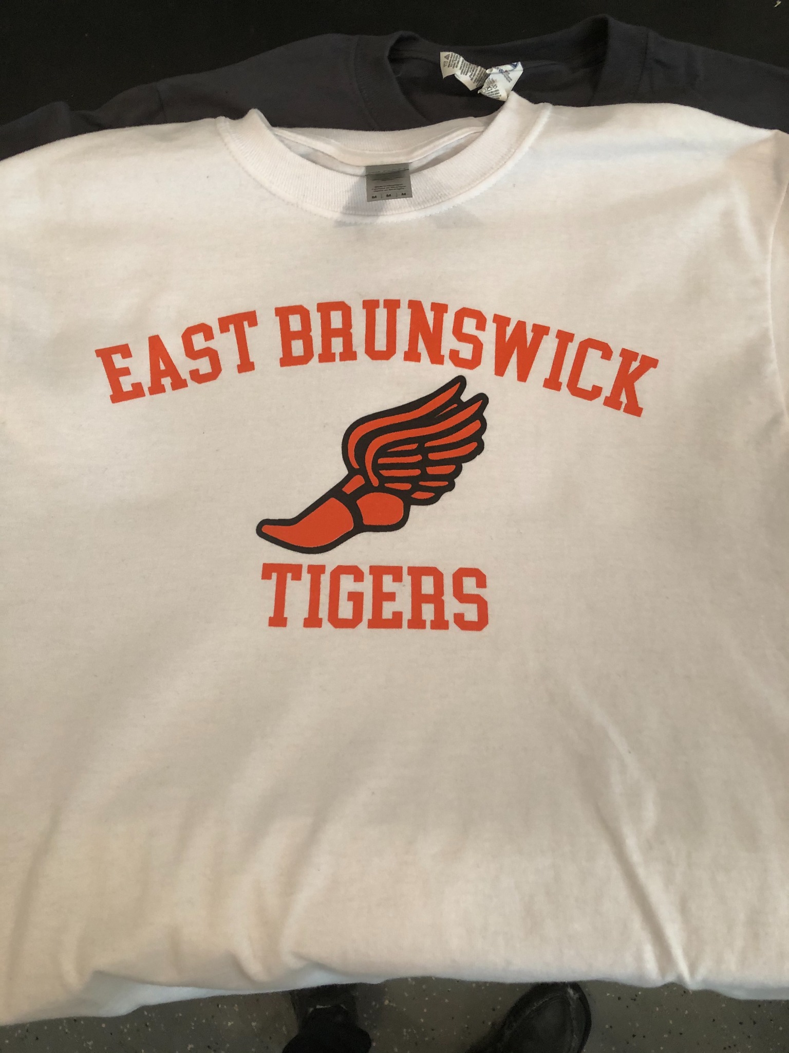 White East Brunswick Tigers shirt with an orange and black winged shoe design
