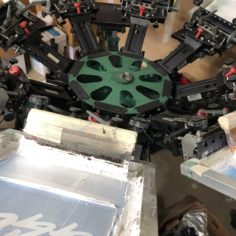 Screen-printing press with white ink and squeegees at the Atlas shop